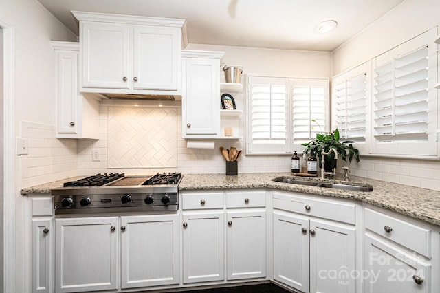 kitchen with backsplash, light stone counters, white cabinets, and stainless steel gas stovetop