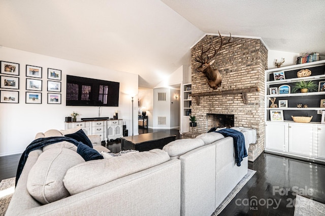 living room featuring dark hardwood / wood-style floors, built in shelves, a fireplace, and vaulted ceiling