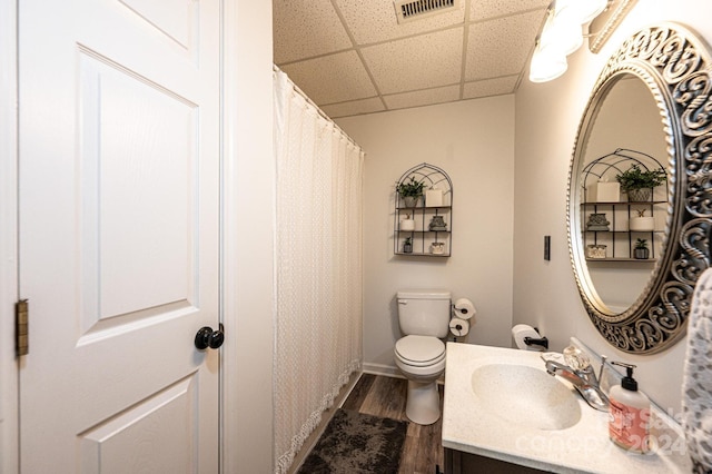 bathroom featuring vanity, hardwood / wood-style flooring, toilet, and a drop ceiling