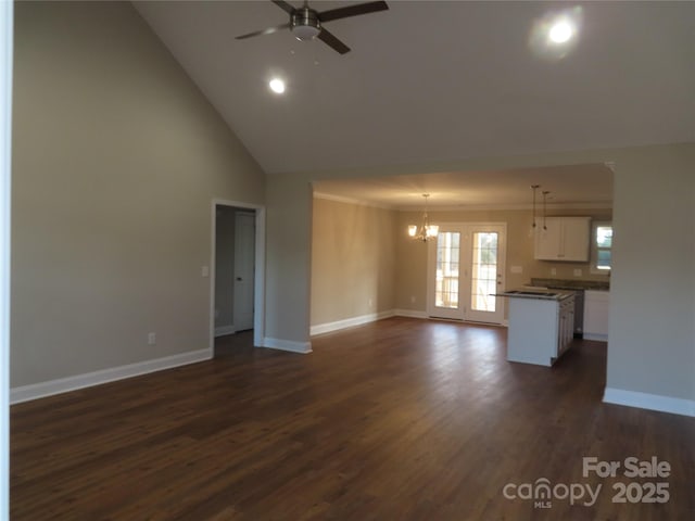 unfurnished living room with high vaulted ceiling, ceiling fan with notable chandelier, and dark hardwood / wood-style flooring