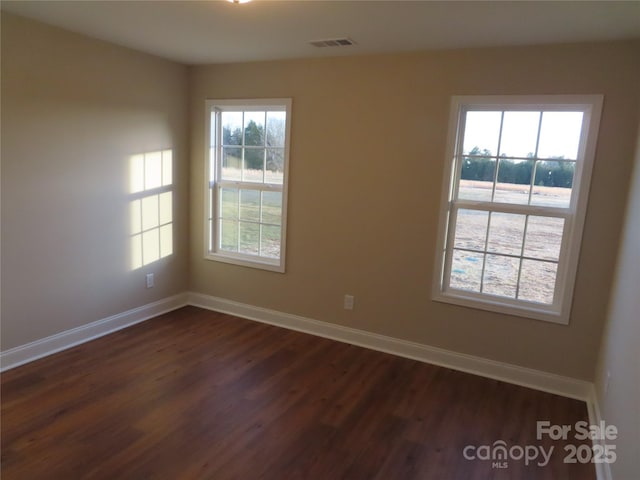 unfurnished room with dark hardwood / wood-style flooring and a wealth of natural light