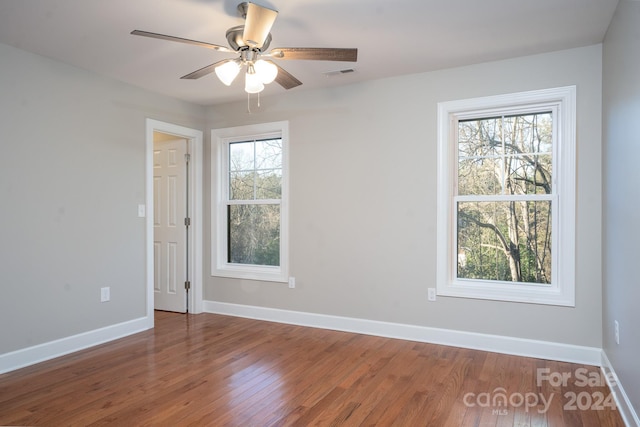 spare room featuring plenty of natural light, dark wood-type flooring, and ceiling fan