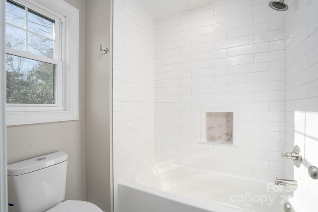 bathroom with tiled shower / bath combo and toilet