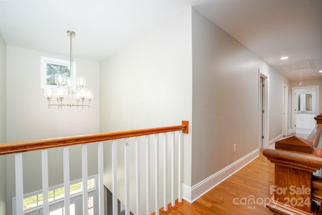 hall featuring light wood-type flooring and an inviting chandelier