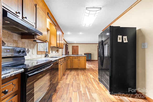 kitchen featuring sink, kitchen peninsula, crown molding, light hardwood / wood-style floors, and black appliances