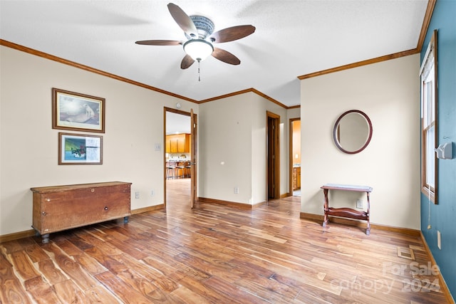 spare room with a textured ceiling, light hardwood / wood-style flooring, ceiling fan, and crown molding