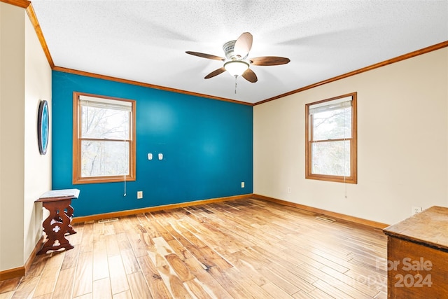 empty room with a textured ceiling, light hardwood / wood-style flooring, a wealth of natural light, and ceiling fan