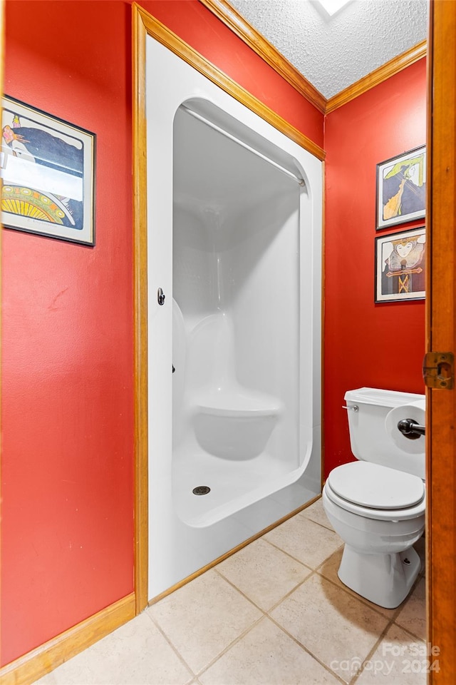 bathroom with toilet, a textured ceiling, and tile patterned floors