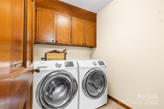 washroom with washing machine and clothes dryer, cabinets, and a textured ceiling