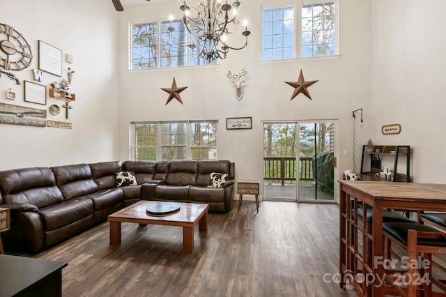 living room featuring a chandelier, a wealth of natural light, wood-type flooring, and a high ceiling