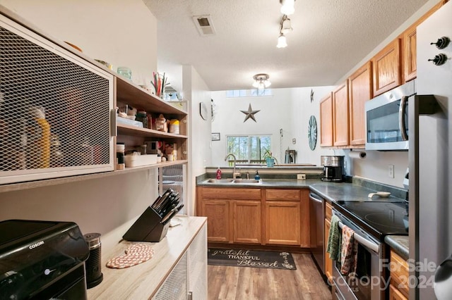 kitchen featuring a textured ceiling, light hardwood / wood-style floors, sink, and stainless steel appliances