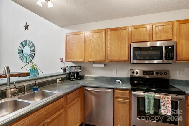 kitchen with a textured ceiling, sink, and appliances with stainless steel finishes