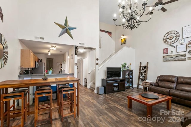 living room with a chandelier, a towering ceiling, and dark wood-type flooring