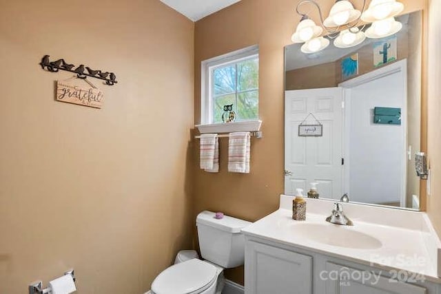 bathroom with vanity, an inviting chandelier, and toilet