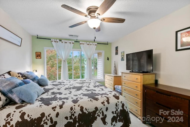 carpeted bedroom featuring ceiling fan and a textured ceiling