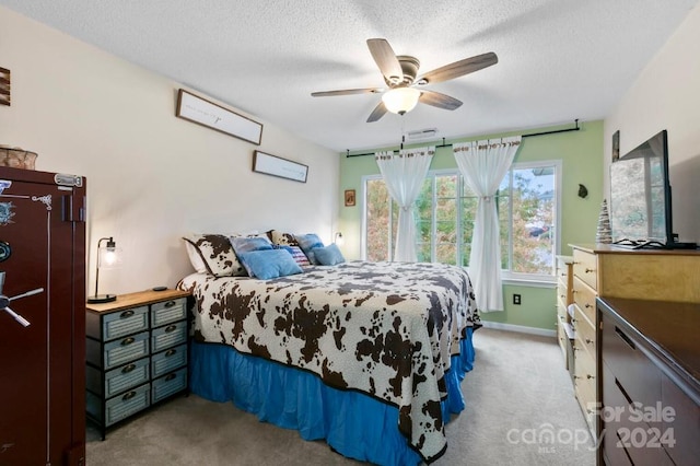 bedroom featuring a textured ceiling, light colored carpet, and ceiling fan