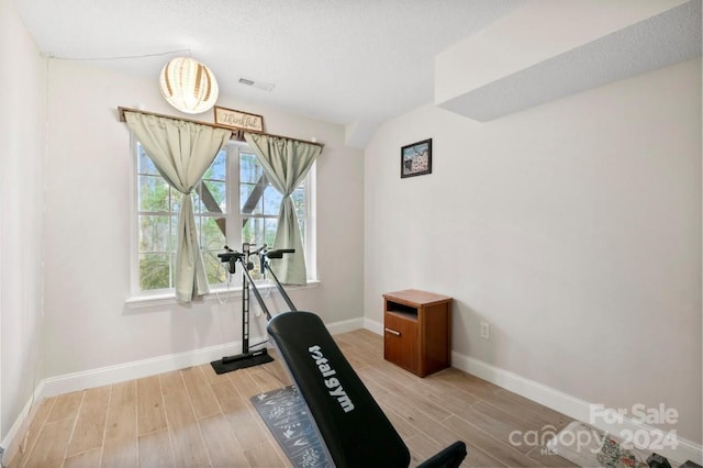 workout room featuring wood-type flooring and a textured ceiling