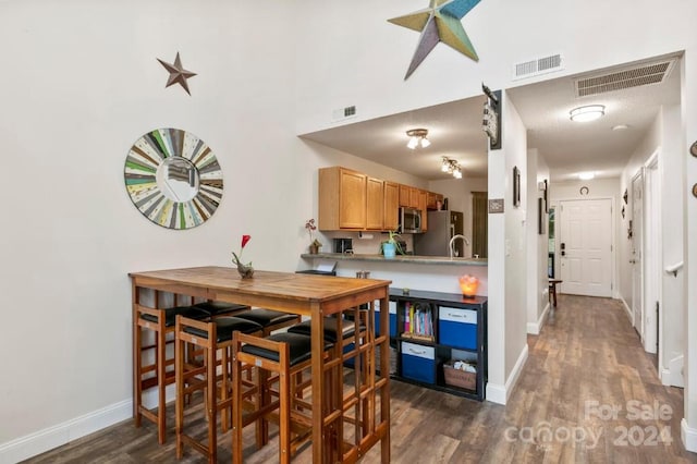 kitchen with a textured ceiling, dark wood-type flooring, and appliances with stainless steel finishes