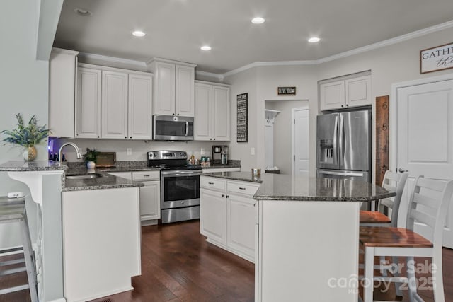 kitchen with appliances with stainless steel finishes, a kitchen bar, a sink, and a center island