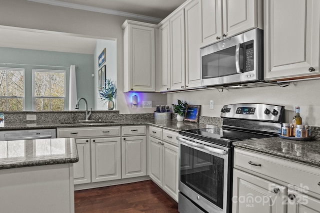 kitchen featuring white cabinets, dark wood-style floors, appliances with stainless steel finishes, ornamental molding, and a sink