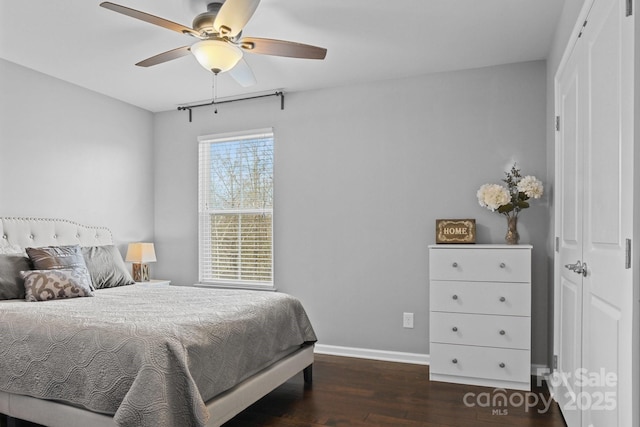 bedroom with ceiling fan, dark wood-type flooring, and baseboards