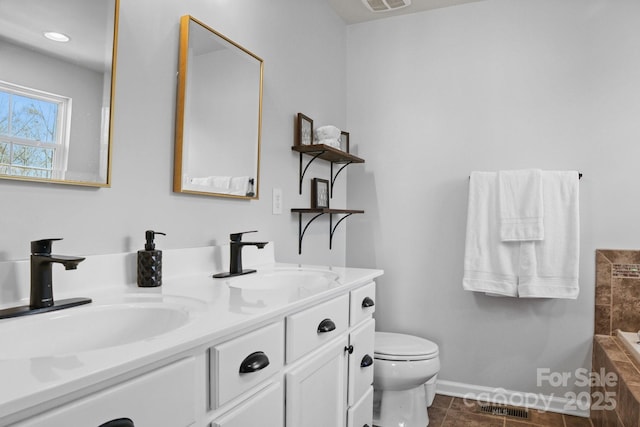 bathroom with visible vents, a sink, toilet, and double vanity