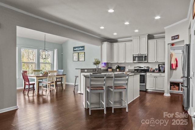 kitchen featuring stainless steel appliances, dark wood-type flooring, white cabinets, ornamental molding, and dark countertops