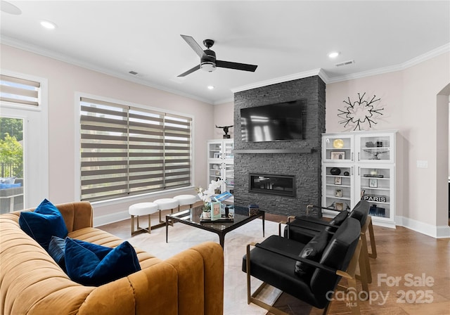 living room featuring ornamental molding, hardwood / wood-style floors, ceiling fan, and a fireplace