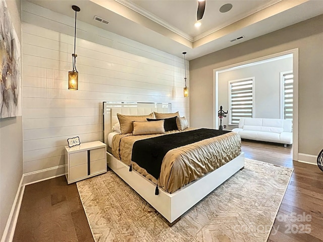 bedroom with hardwood / wood-style flooring, crown molding, a raised ceiling, and ceiling fan