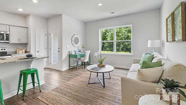 living area with baseboards, dark wood-style flooring, visible vents, and recessed lighting