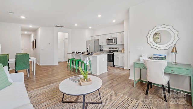 living room featuring recessed lighting, baseboards, visible vents, and light wood finished floors