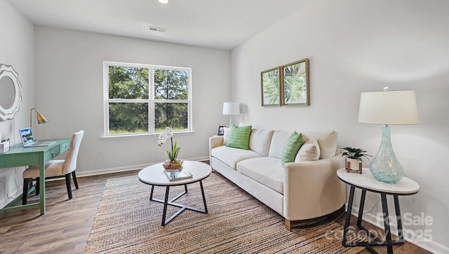 living area featuring baseboards, visible vents, and wood finished floors