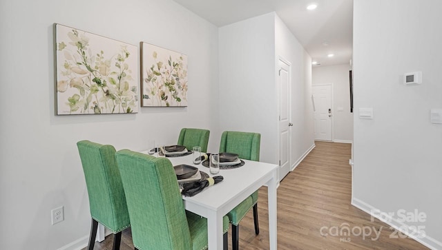 dining area with baseboards, wood finished floors, and recessed lighting