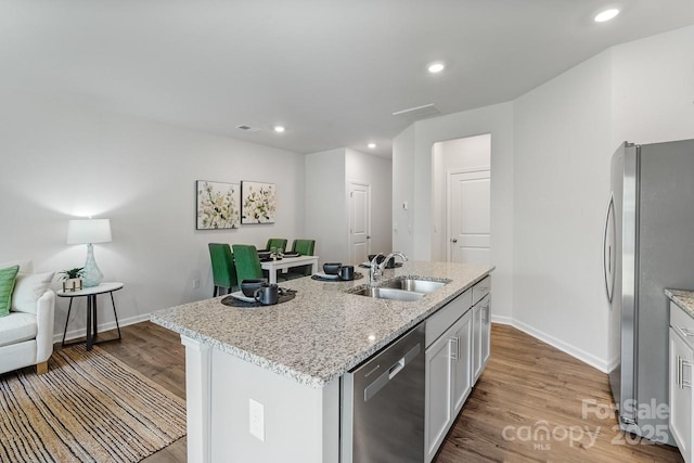 kitchen featuring light wood finished floors, baseboards, appliances with stainless steel finishes, a sink, and recessed lighting