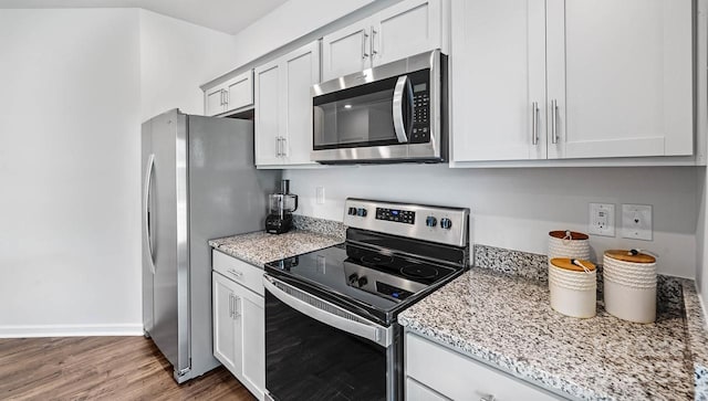 kitchen featuring appliances with stainless steel finishes, light stone countertops, baseboards, and wood finished floors