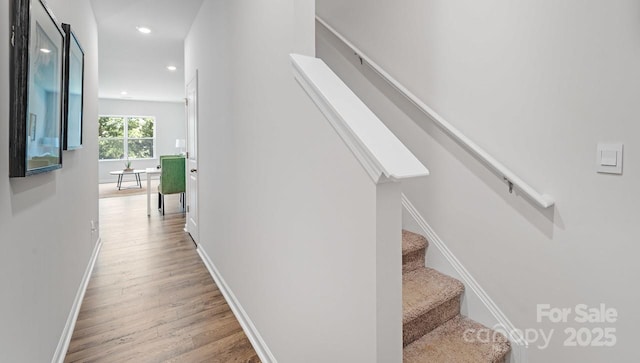 staircase with baseboards, wood finished floors, and recessed lighting