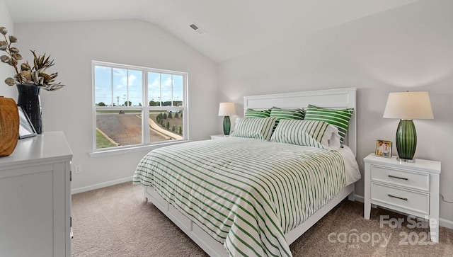 carpeted bedroom featuring lofted ceiling, baseboards, and visible vents