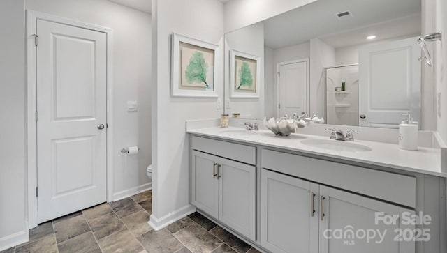 bathroom featuring toilet, a stall shower, visible vents, and a sink