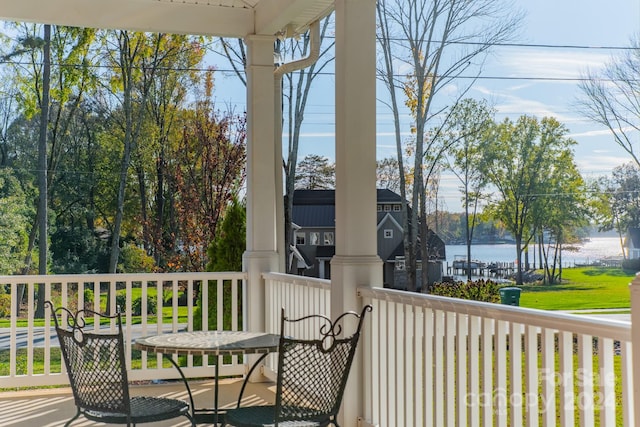 deck with covered porch and a water view