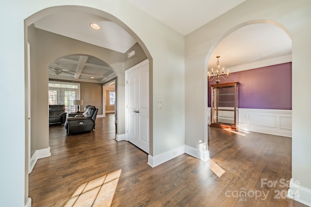 hall featuring coffered ceiling, an inviting chandelier, beamed ceiling, dark hardwood / wood-style floors, and crown molding