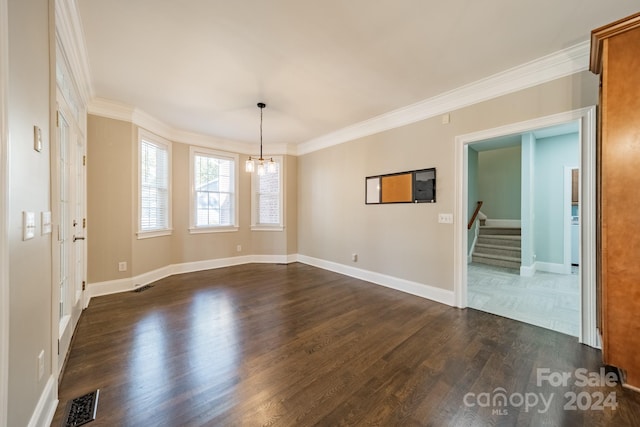 empty room with dark hardwood / wood-style flooring, ornamental molding, and a notable chandelier