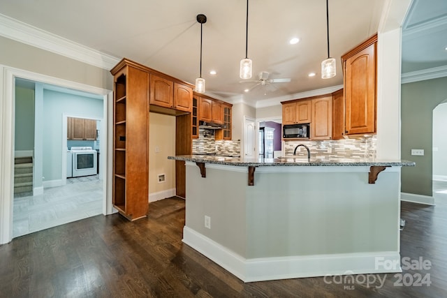 kitchen featuring dark stone counters, a breakfast bar, ceiling fan, pendant lighting, and dark hardwood / wood-style floors