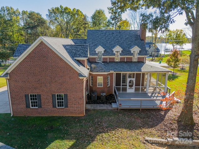 view of front facade with central AC unit, a wooden deck, and a front lawn