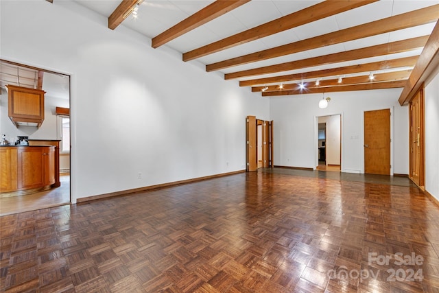 unfurnished living room with beam ceiling, dark parquet flooring, and track lighting