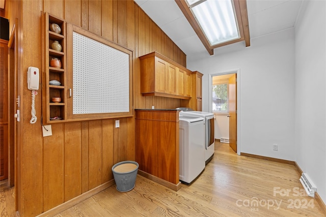 washroom with cabinets, light wood-type flooring, wooden walls, and separate washer and dryer