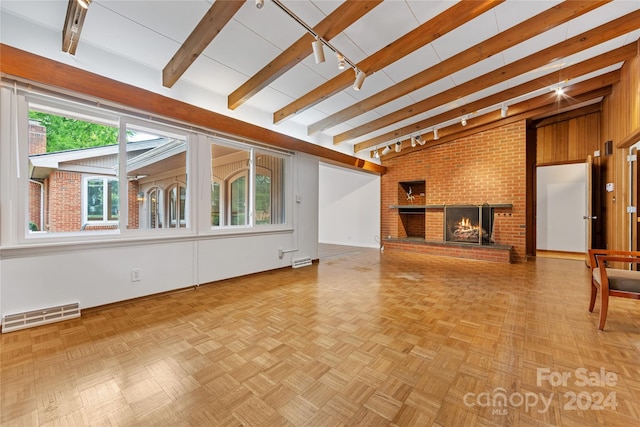 unfurnished living room featuring light parquet floors, beam ceiling, a brick fireplace, and brick wall