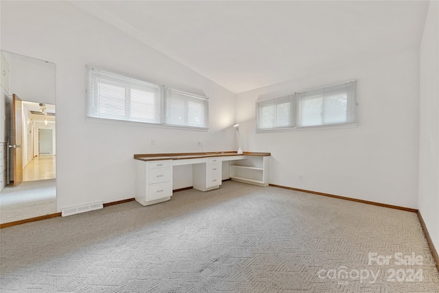 unfurnished office with light carpet, built in desk, and lofted ceiling