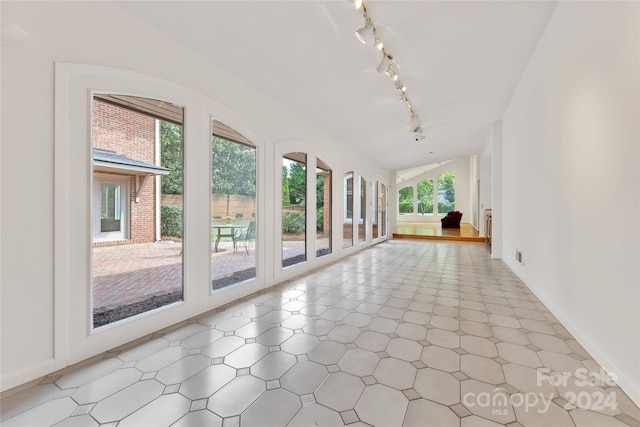 interior space featuring plenty of natural light, rail lighting, and vaulted ceiling