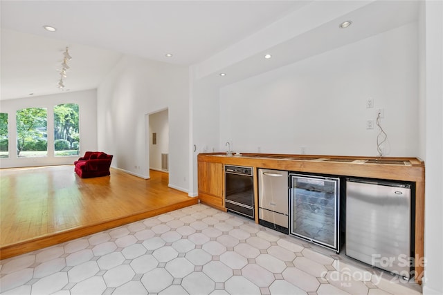 bar featuring wine cooler, light hardwood / wood-style floors, stainless steel refrigerator, and sink