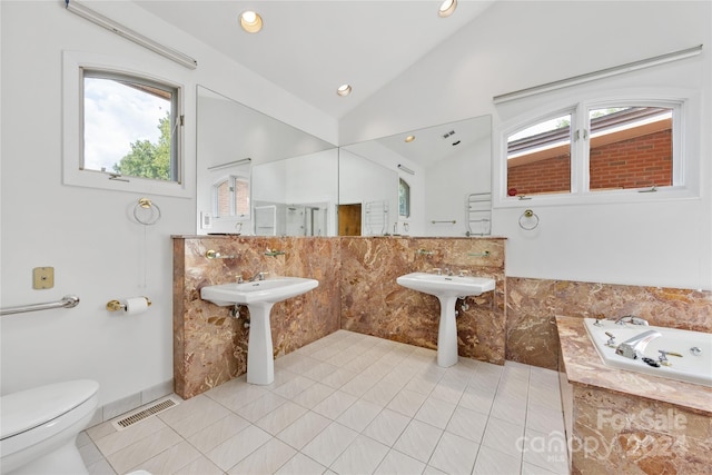 bathroom featuring tile patterned floors, tiled tub, lofted ceiling, and toilet